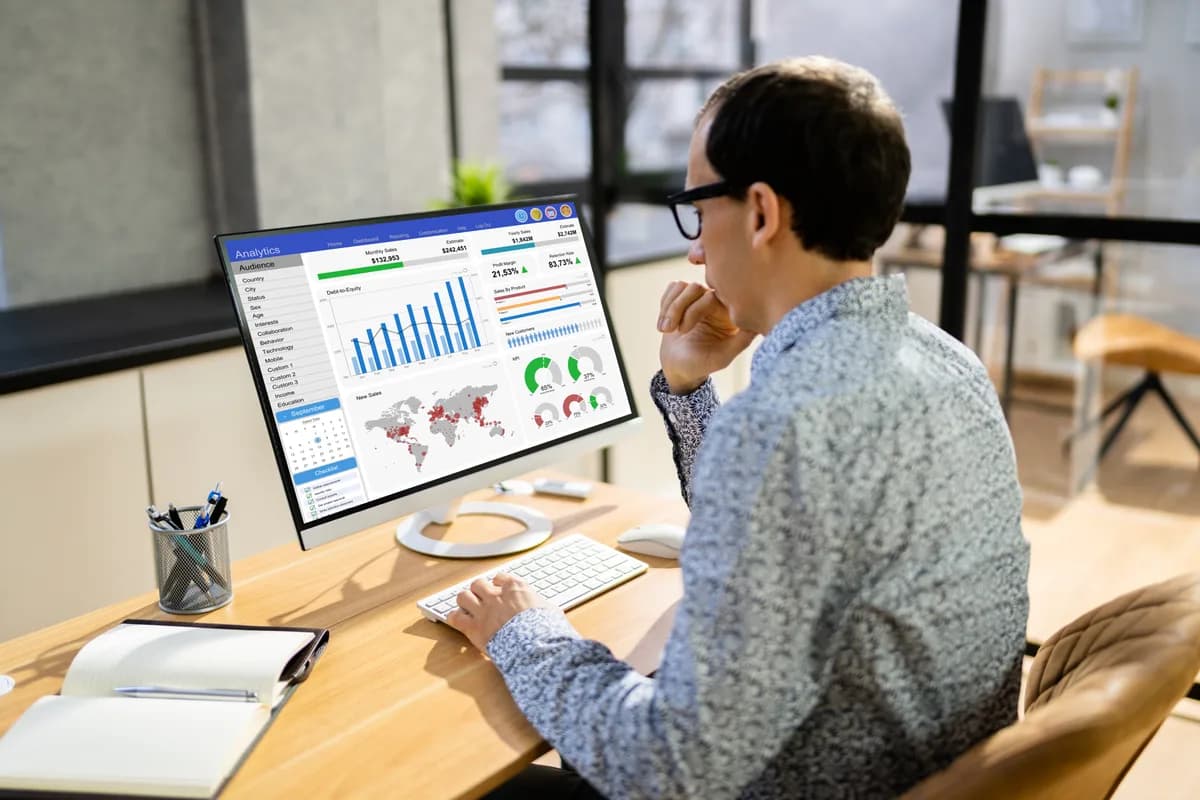 A marketing analyst reviewing conversion actions and bidding settings on a Google Ads dashboard at a desk