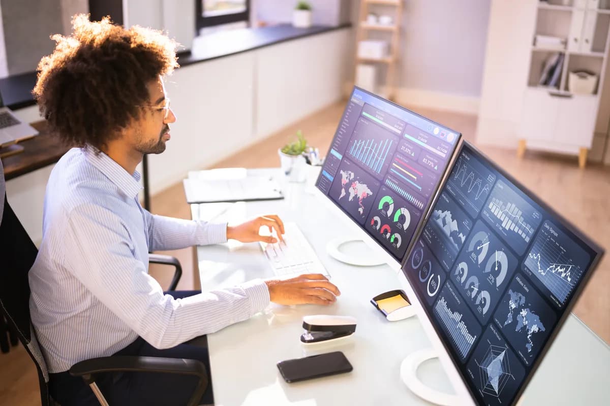 An online store owner comparing Shopify order data and a Google Ads conversion report side by side on two monitors