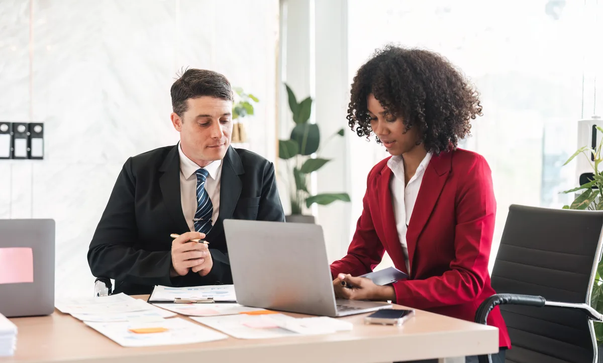 A mold remediation company owner reviewing campaign and lead performance on a laptop with a marketing consultant across the table