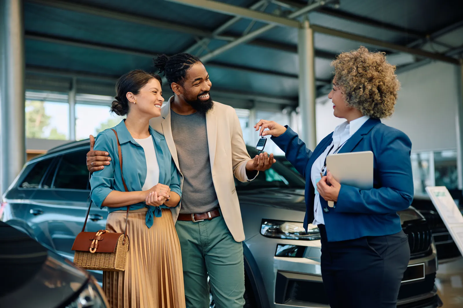 Salesperson handing car keys to a couple at a dealership