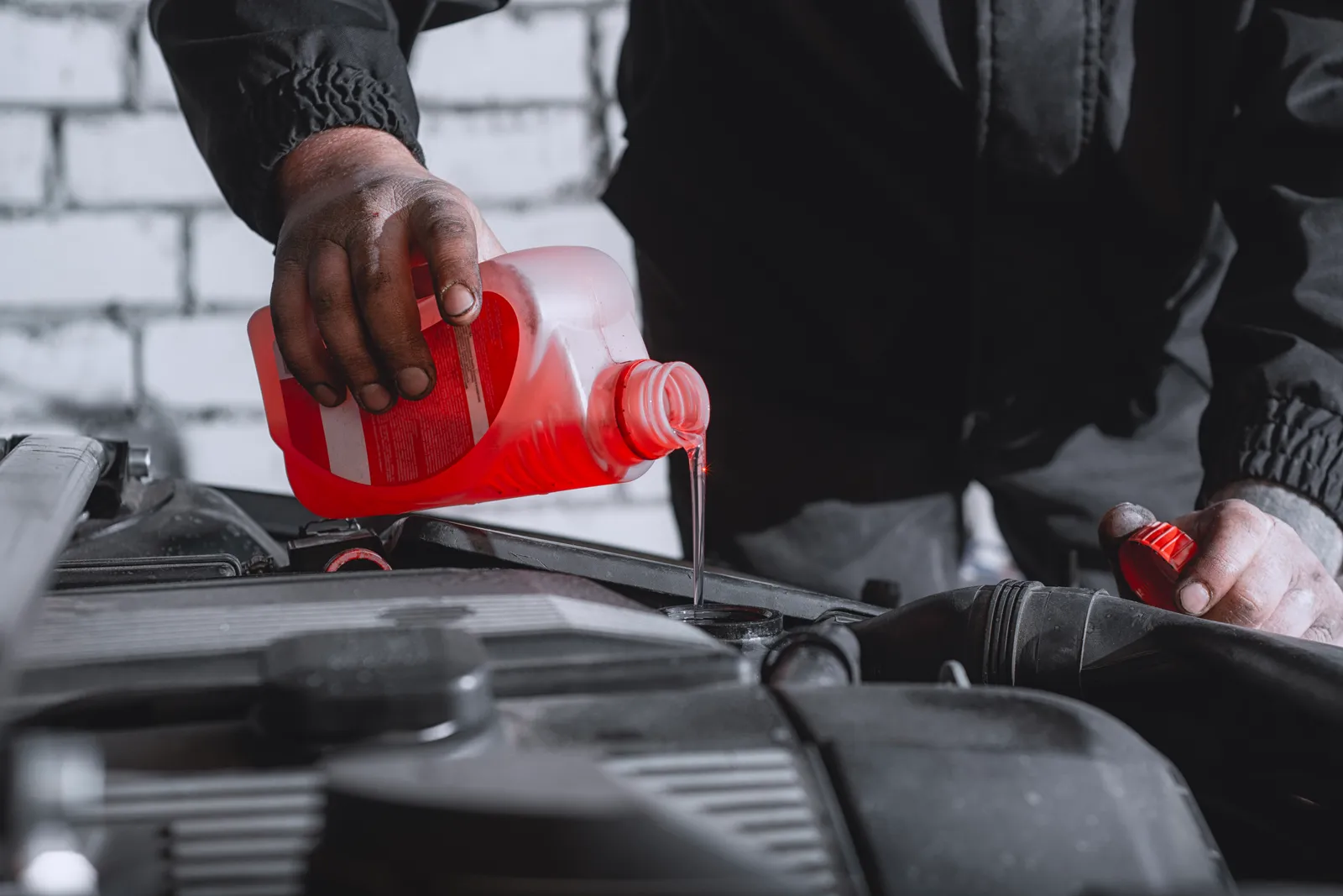 Mechanic topping up coolant on a car in a repair bay
