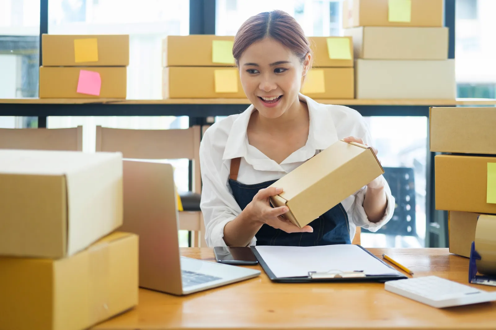 Store owner packing orders beside her laptop