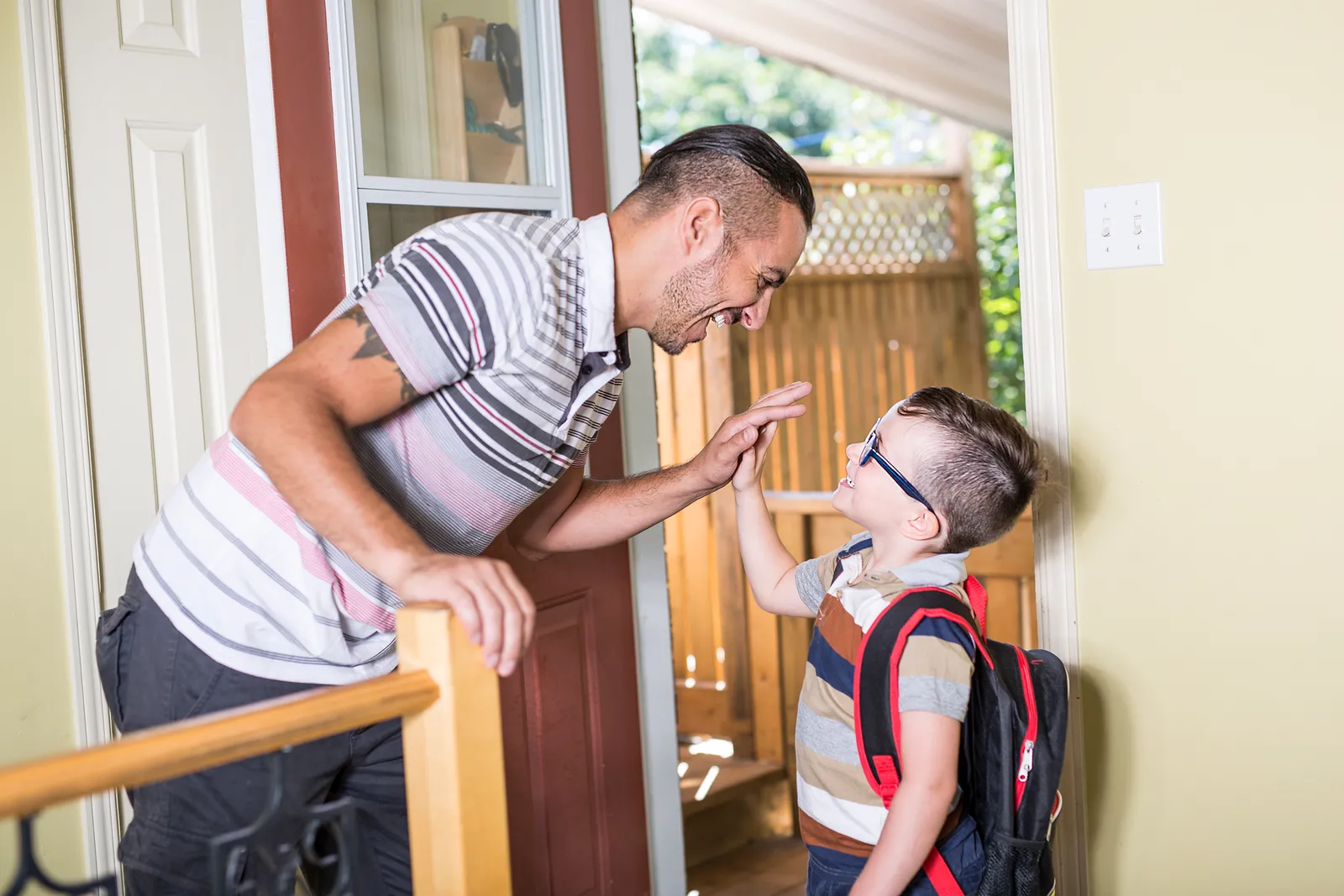 Father sending his son off to school with a high five