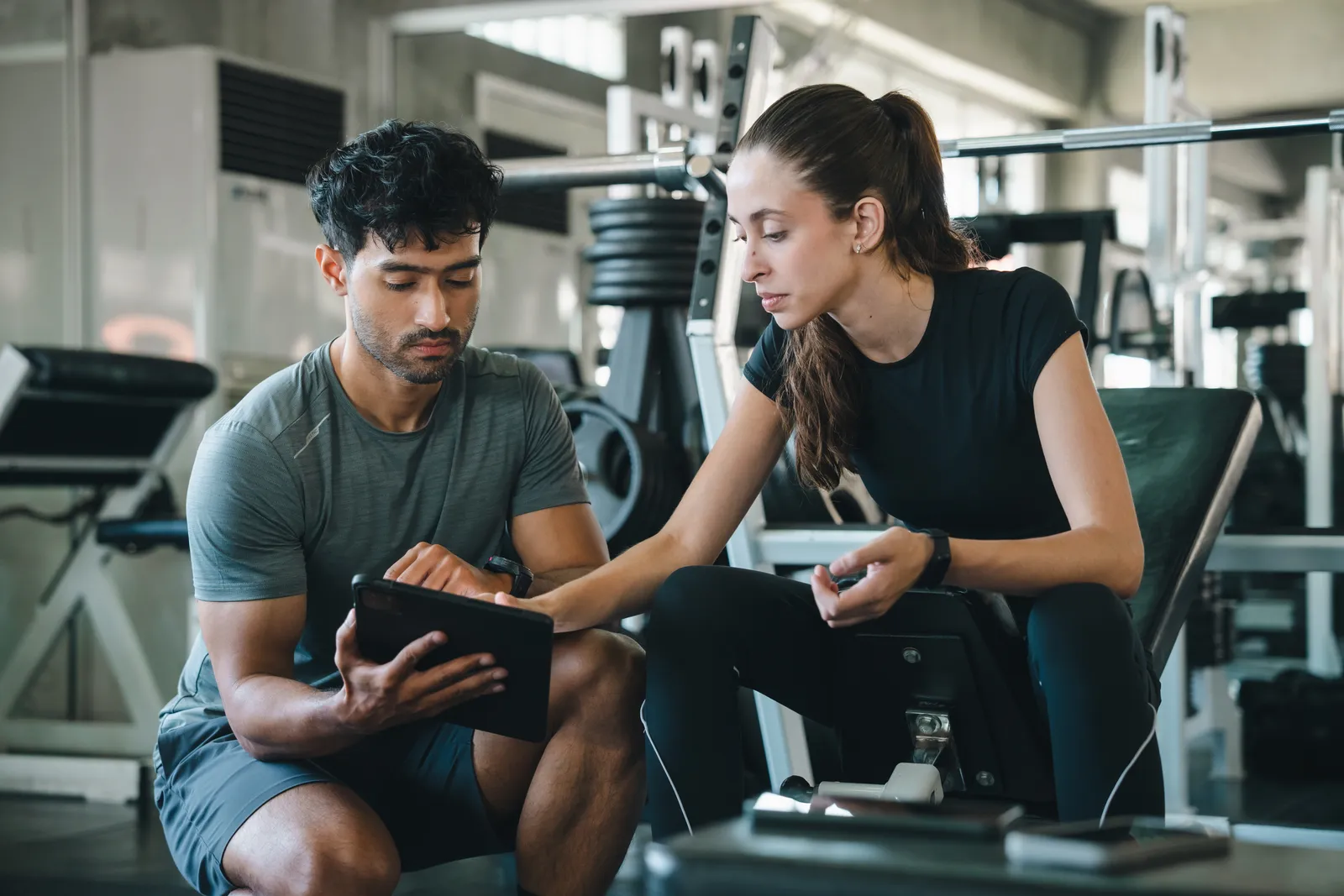 Trainer reviewing a workout plan on a tablet with a client in the gym
