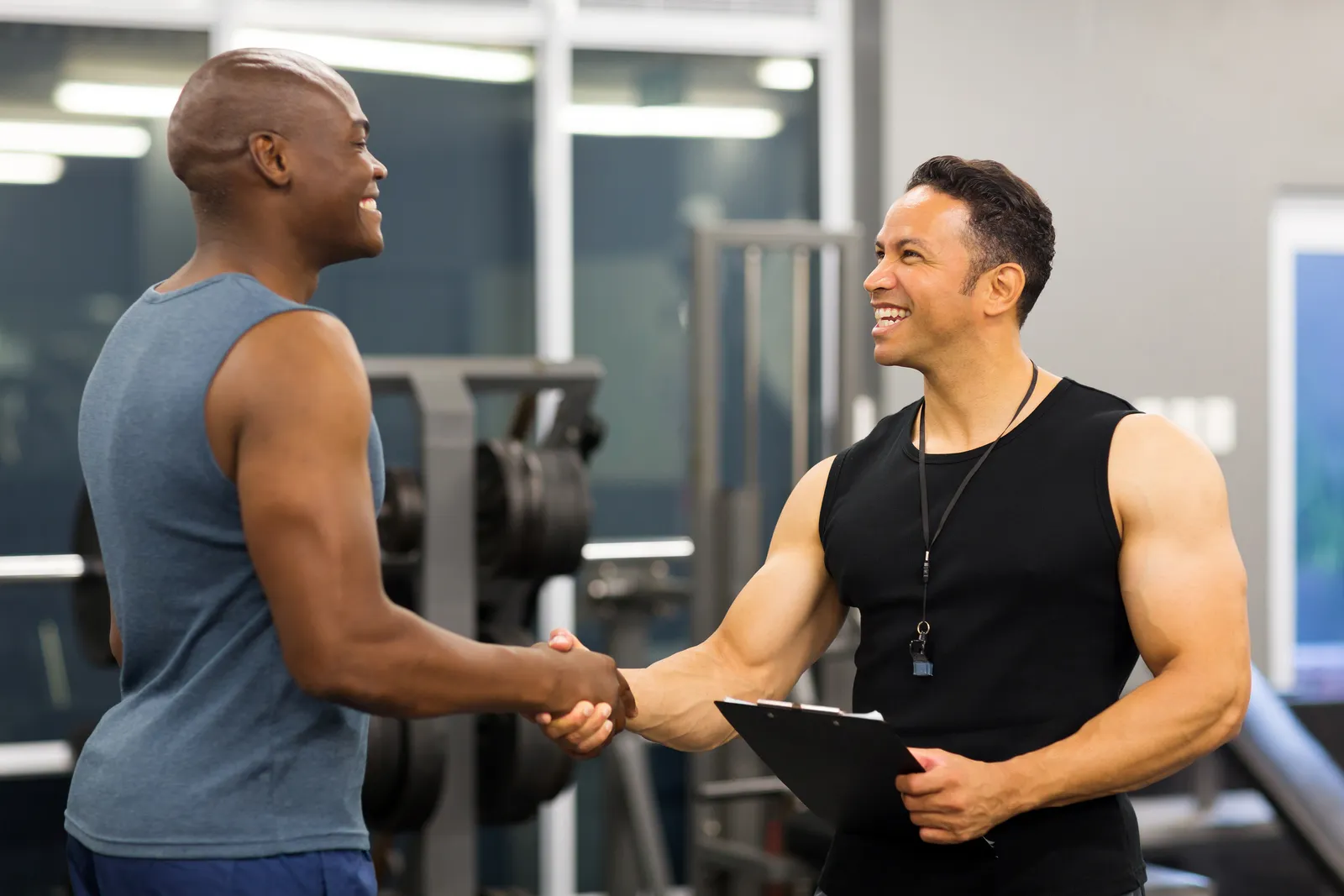Personal trainer welcoming a client with a handshake on the gym floor