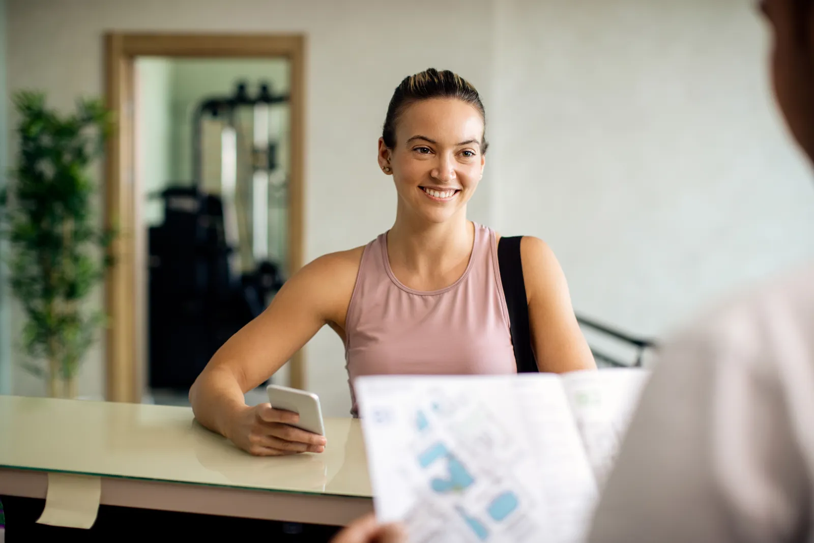 Member checking the class schedule on her phone at the gym front desk