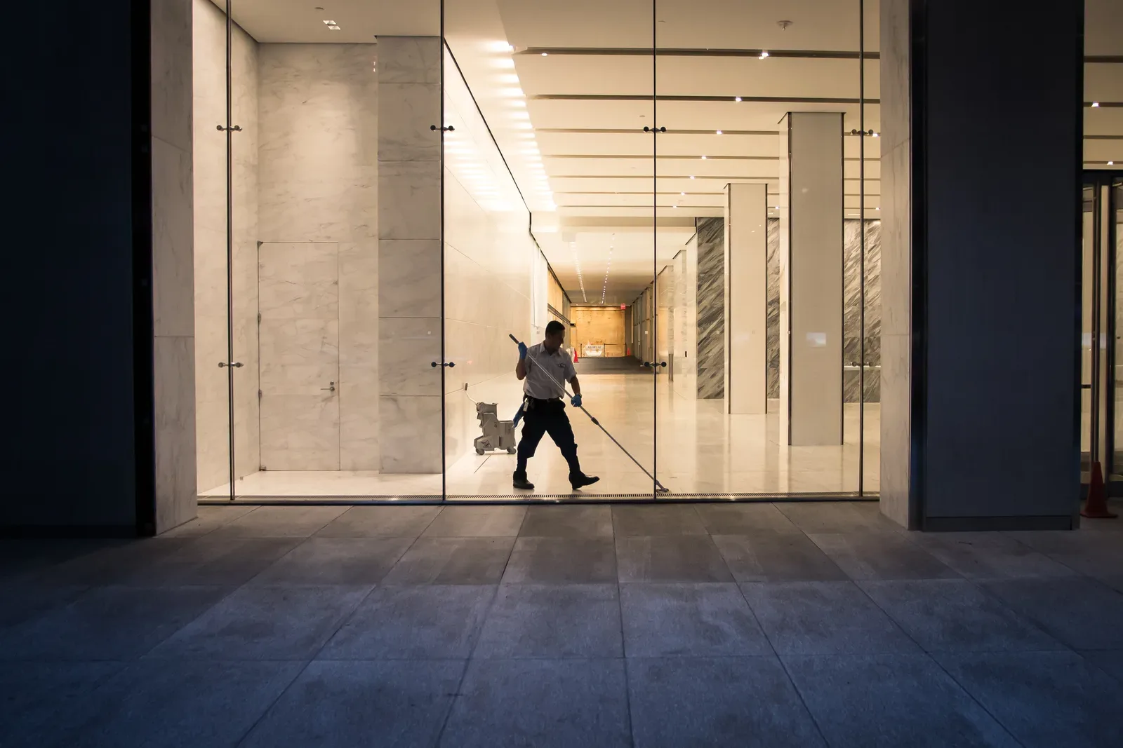 Commercial cleaner in uniform polishing the floor of an office building lobby after hours