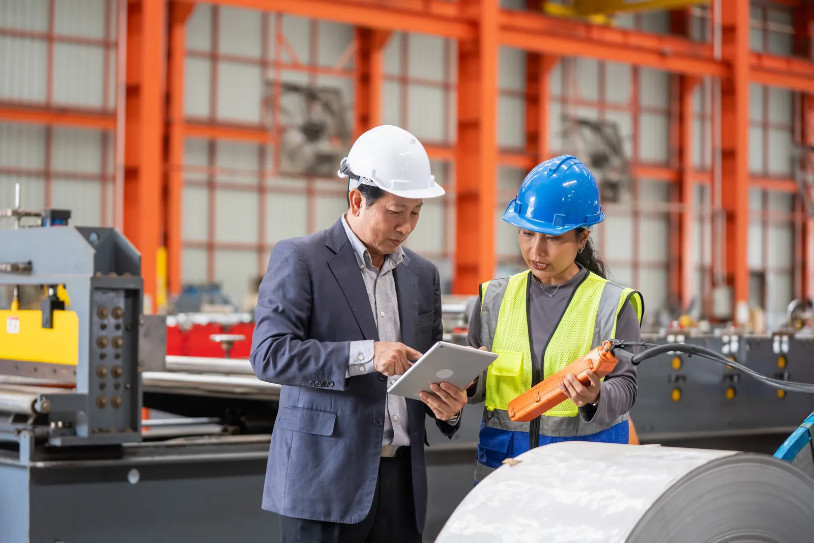 Consultant reviewing production notes with a plant manager on the factory floor