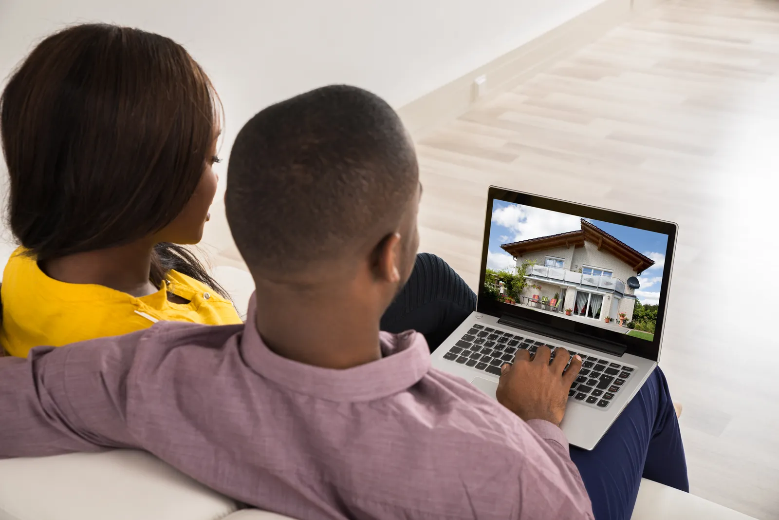 Couple browsing home listings on a laptop at home