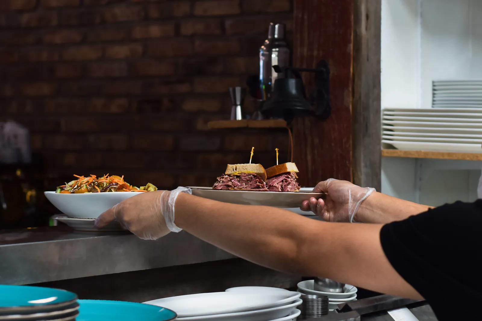 Plated dishes being passed over a restaurant kitchen counter