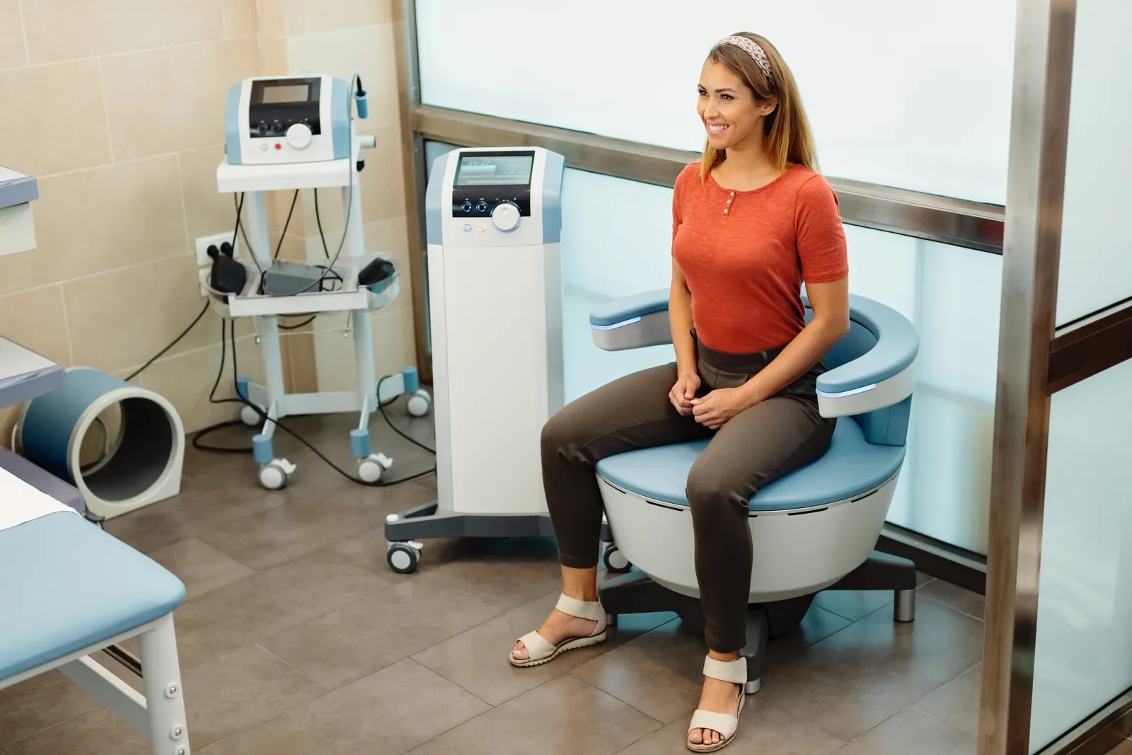 Patient seated in a treatment chair beside TMS equipment in a clinic room