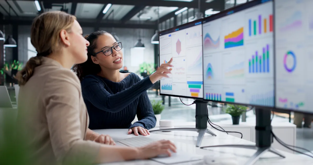 Two performance marketing specialists reviewing Google Ads campaign metrics together on a monitor in a Canadian office
