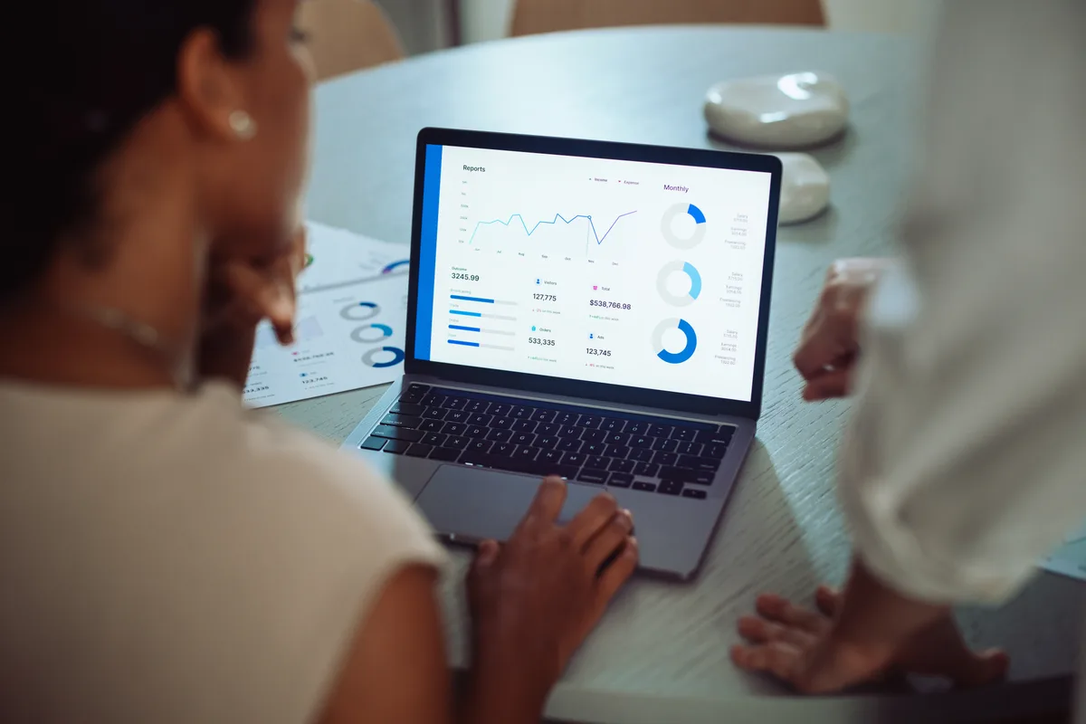 A marketing specialist showing a Google Ads performance dashboard on a laptop to a business owner during an account handover