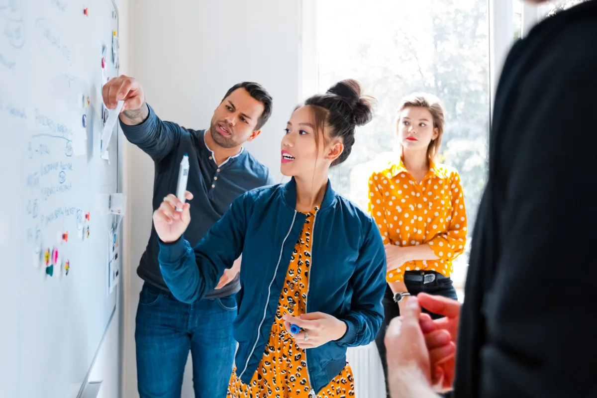 A marketing team mapping the stages of a customer journey on a whiteboard, from first click through to final sale