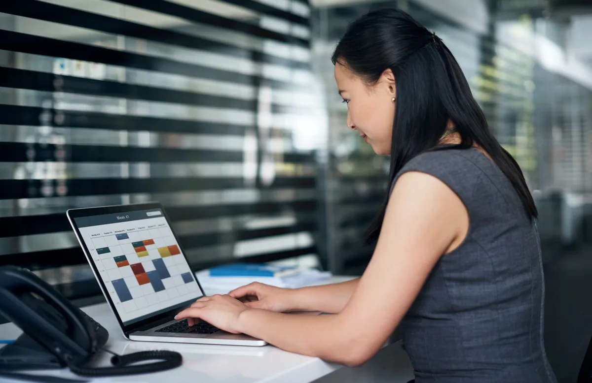 Service business owner reviewing the day's appointment schedule on a laptop at the front counter