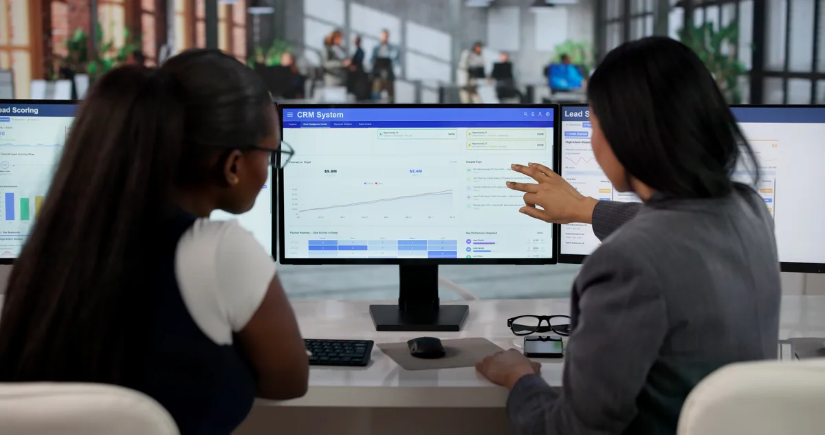 A sales and marketing team reviewing a CRM pipeline on a monitor, tracing leads from first contact to closed deals