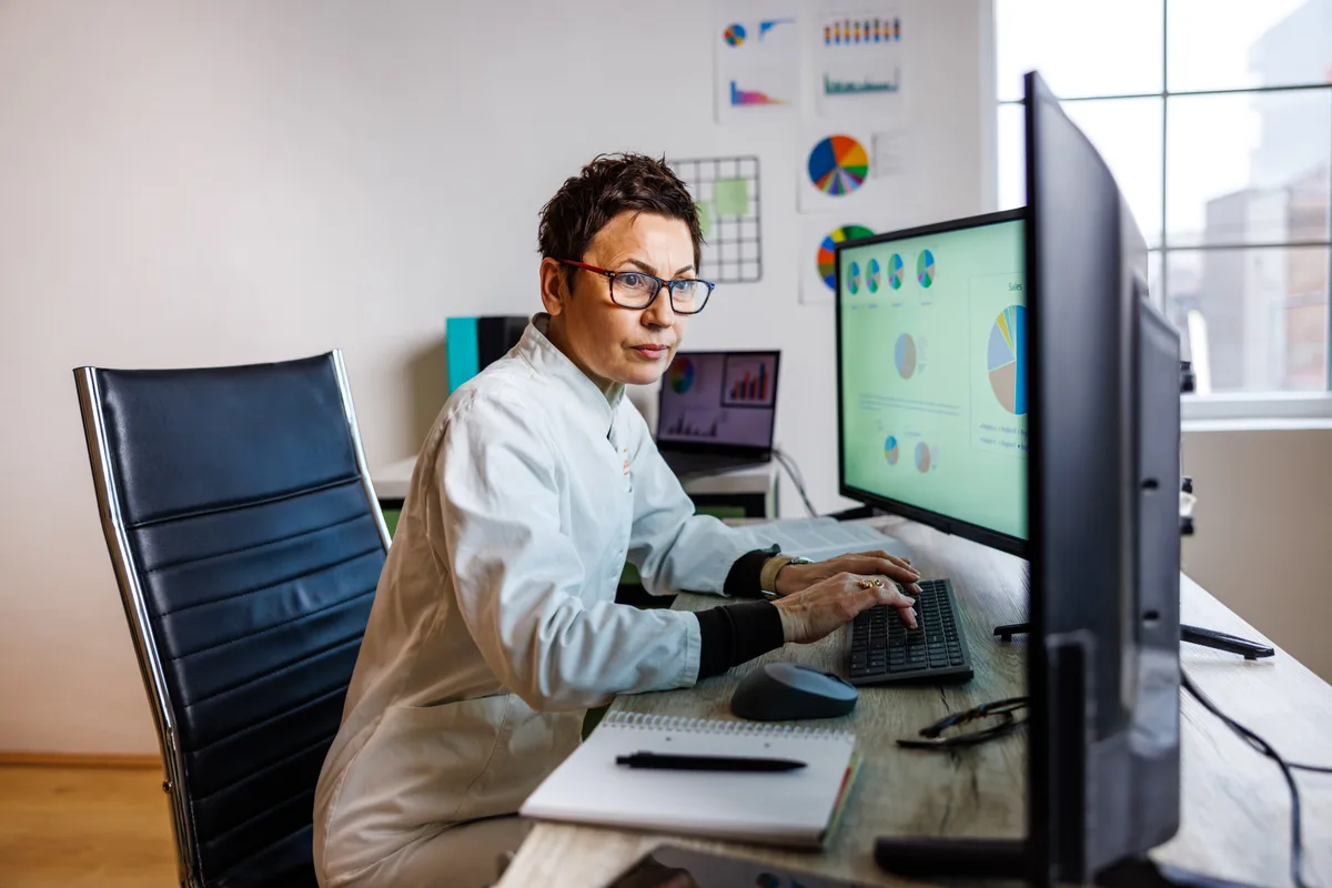 A subject-matter expert reviewing data and source material on a monitor while writing reference content