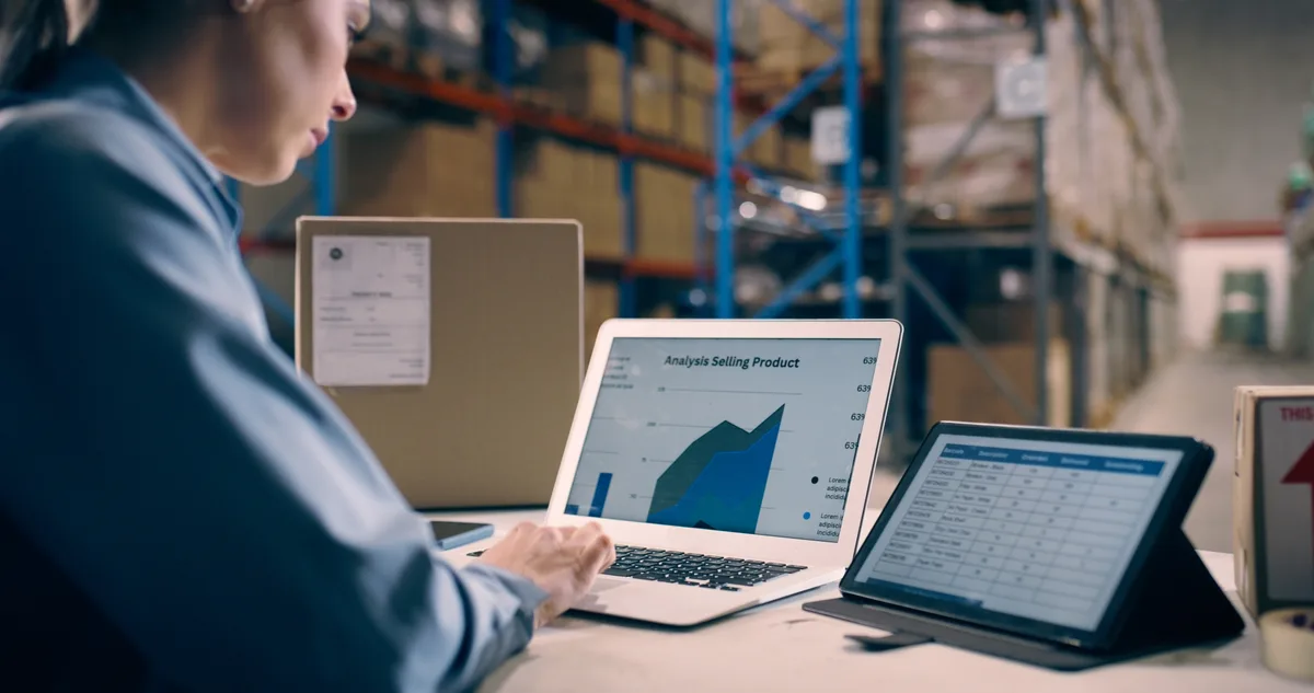 E-commerce store owner reviewing revenue and ROAS data on a laptop beside packed orders