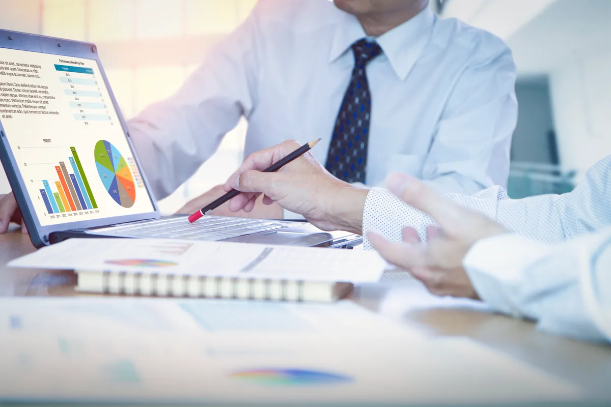 Analyst reviewing cross-site conversion data on two monitors while reconciling booking-platform reports