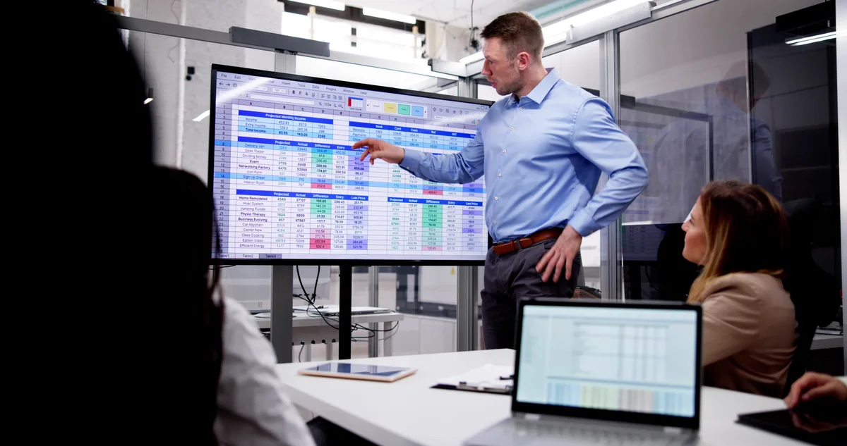 A marketing analyst reviewing a city-by-service tracking grid on a large monitor