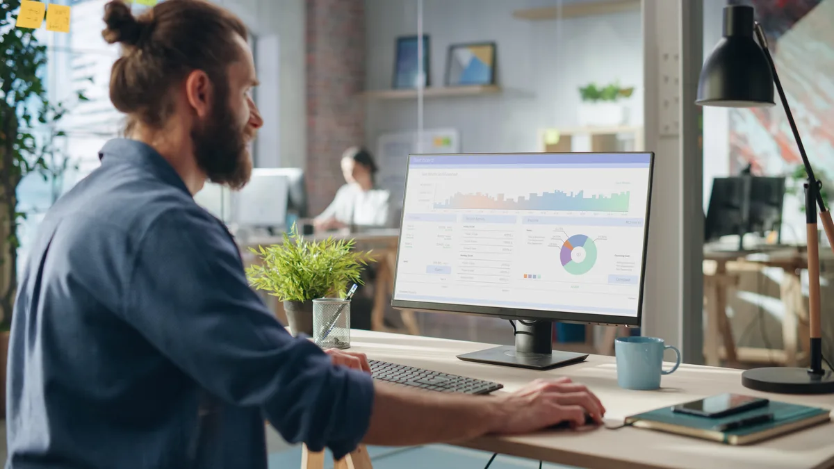 Business owner checking AI search visibility analytics on a desktop monitor in a modern office