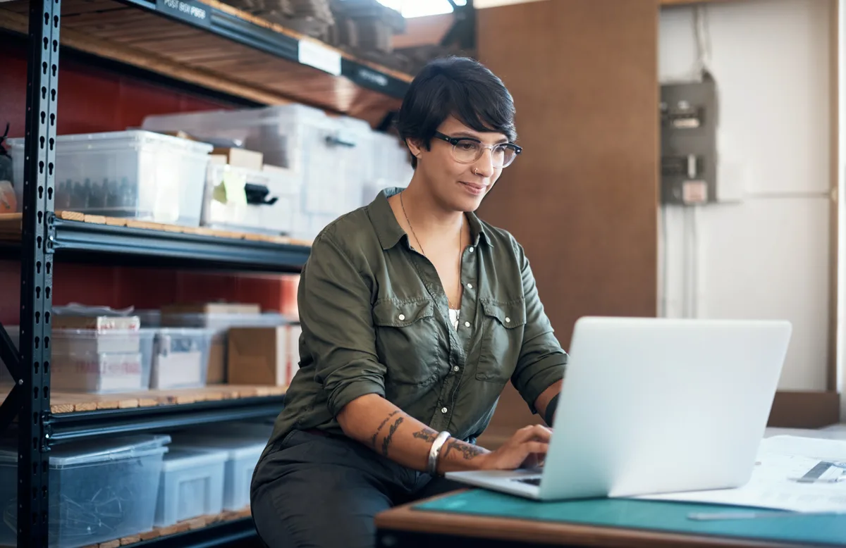 Shopify store owner reviewing automated email flow performance on a laptop beside packed product orders