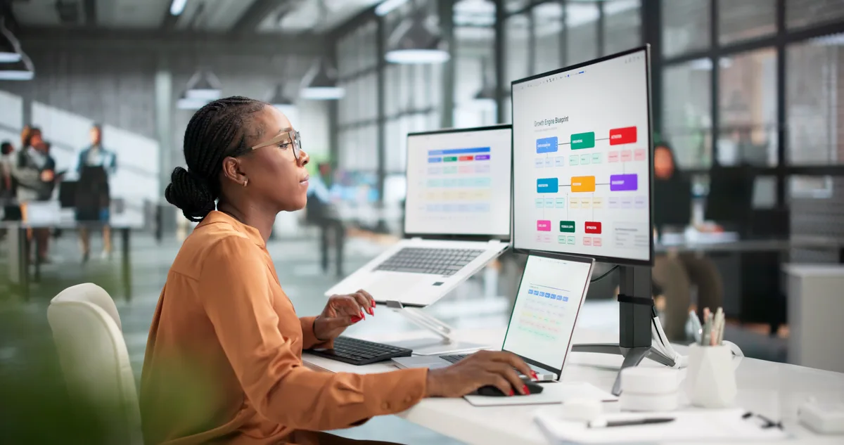 A digital marketing specialist reviewing AI chatbot answers and search rankings side by side on dual monitors