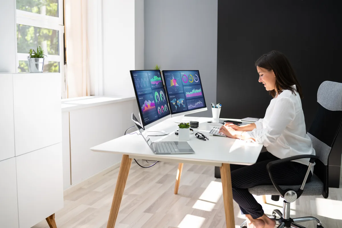 A marketing analyst comparing conversion counts across Google Ads and GA4 dashboards on two monitors to verify tracking accuracy