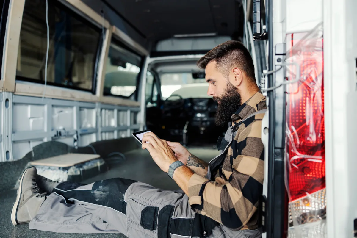 A service business owner reviewing incoming leads on a phone while sitting in a work van