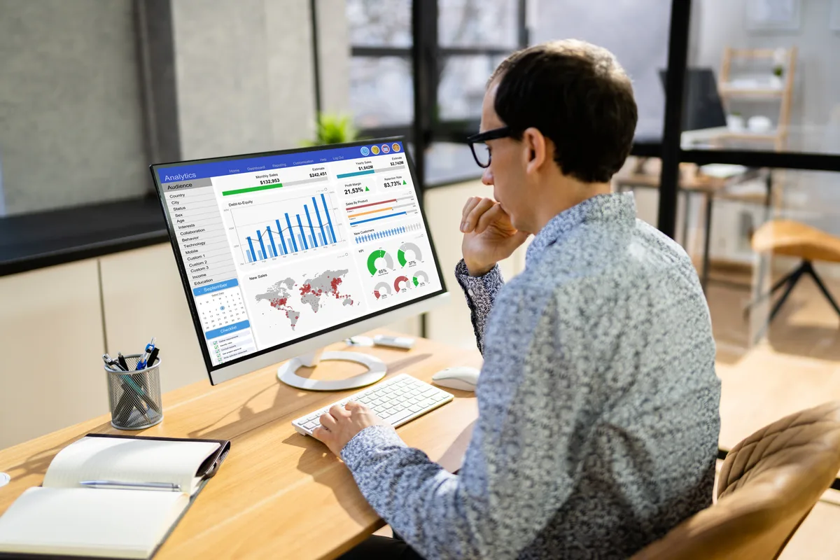 A marketing analyst reviewing conversion actions and bidding settings on a Google Ads dashboard at a desk