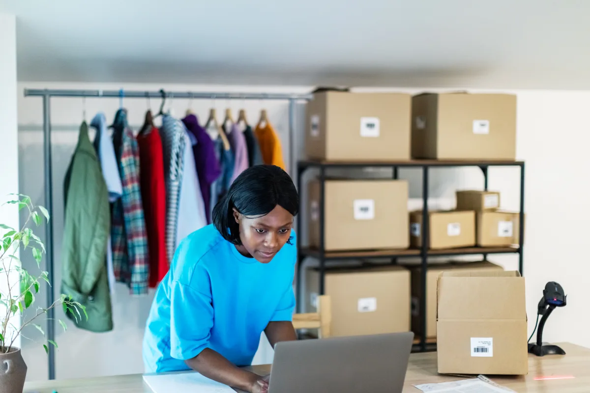 Store owner reviewing Shopify collection pages and product categories on a laptop in a warehouse
