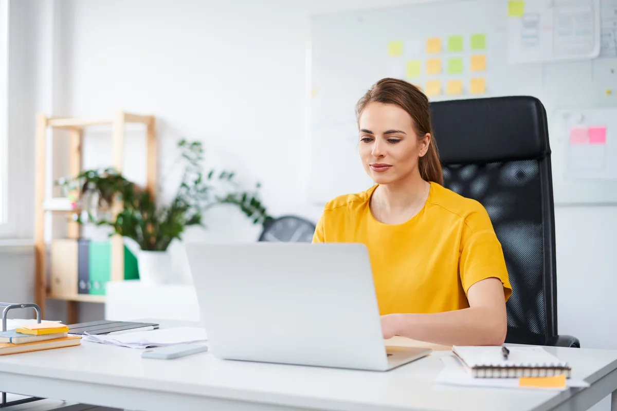 A content strategist editing existing website copy on a laptop while reviewing analytics on a second monitor