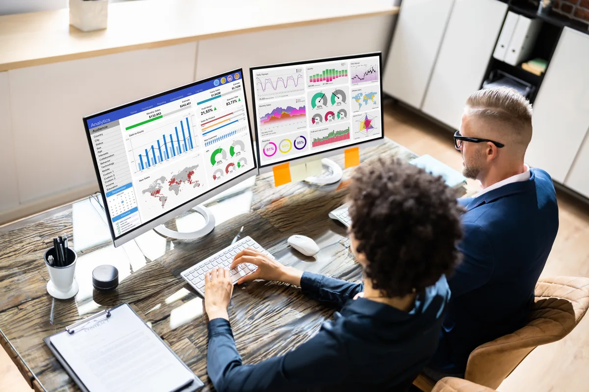 A web developer and marketer reviewing a website analytics dashboard together at a desk during a build