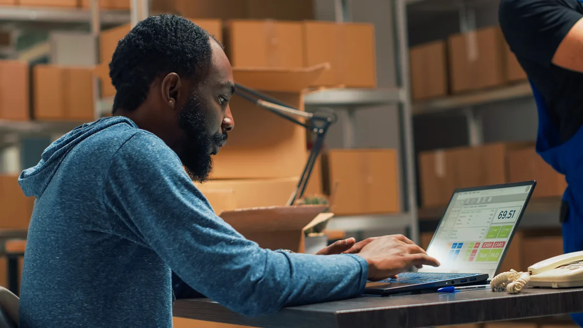 Store owner reviewing automated email flow performance on a laptop beside packed shipping orders