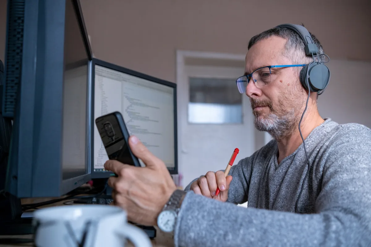Developer reviewing application code and a monitoring dashboard on two screens during routine app maintenance