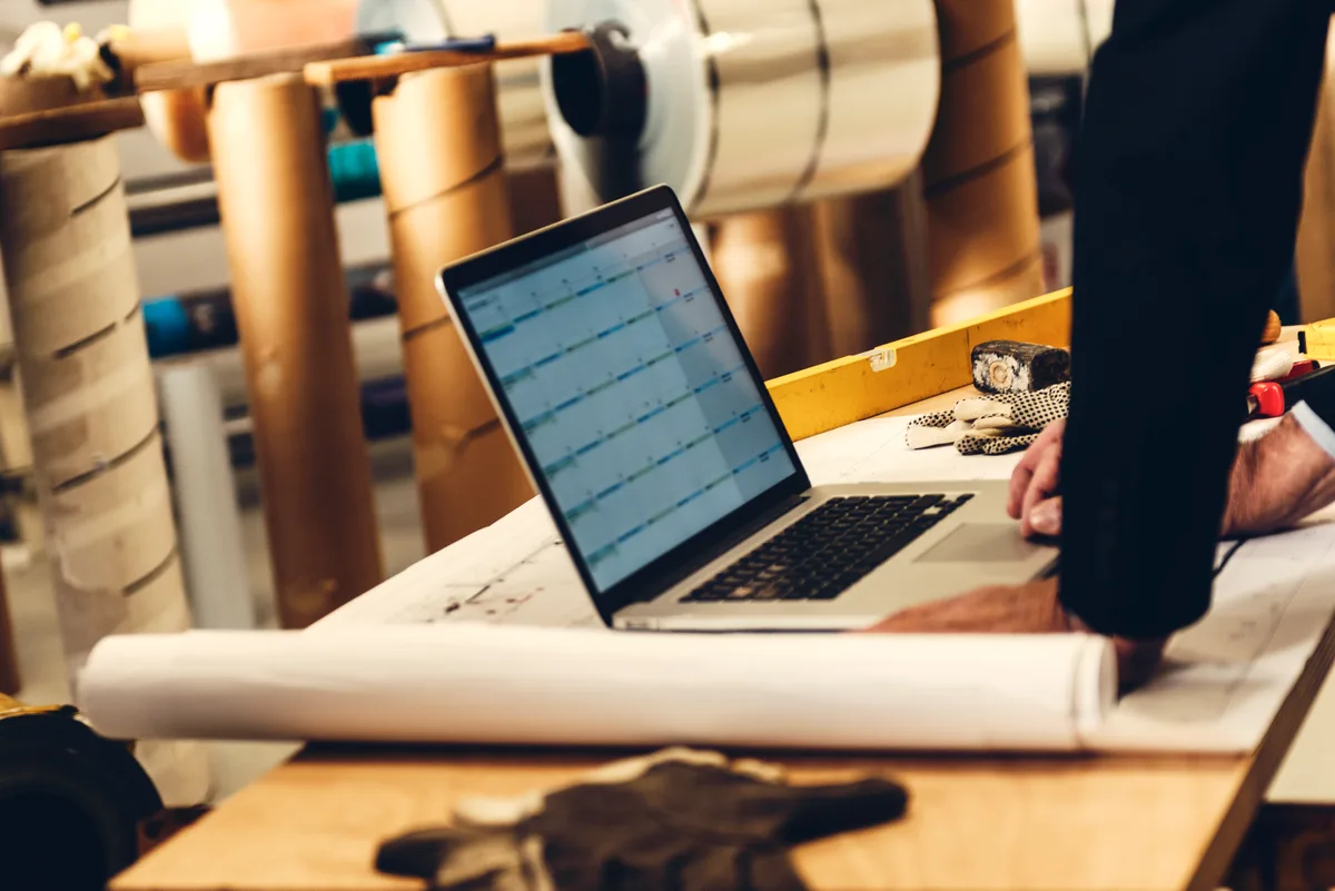 A roofing contractor reviewing job and marketing data on a laptop at a desk in a contractor office