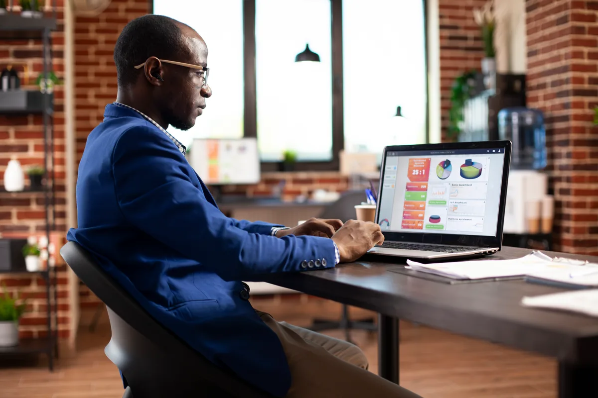 A marketer reviewing declining email open-rate and revenue charts on a laptop dashboard at a desk
