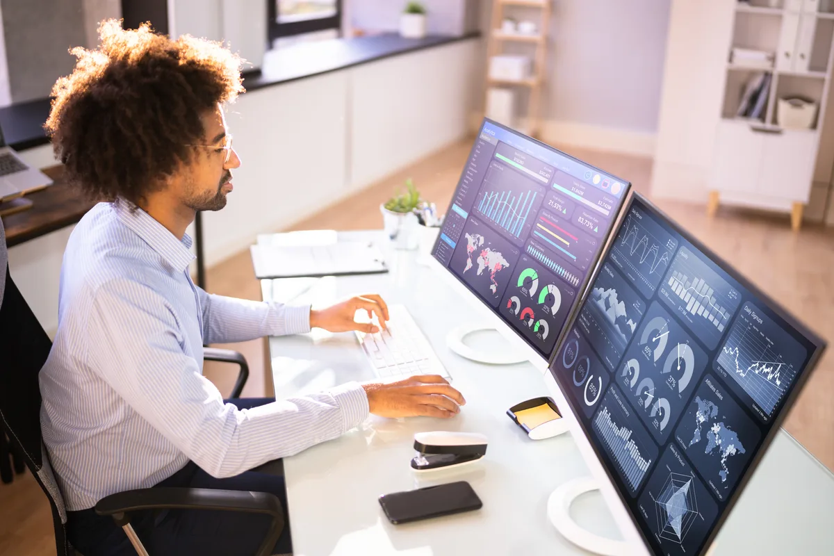 An online store owner comparing Shopify order data and a Google Ads conversion report side by side on two monitors