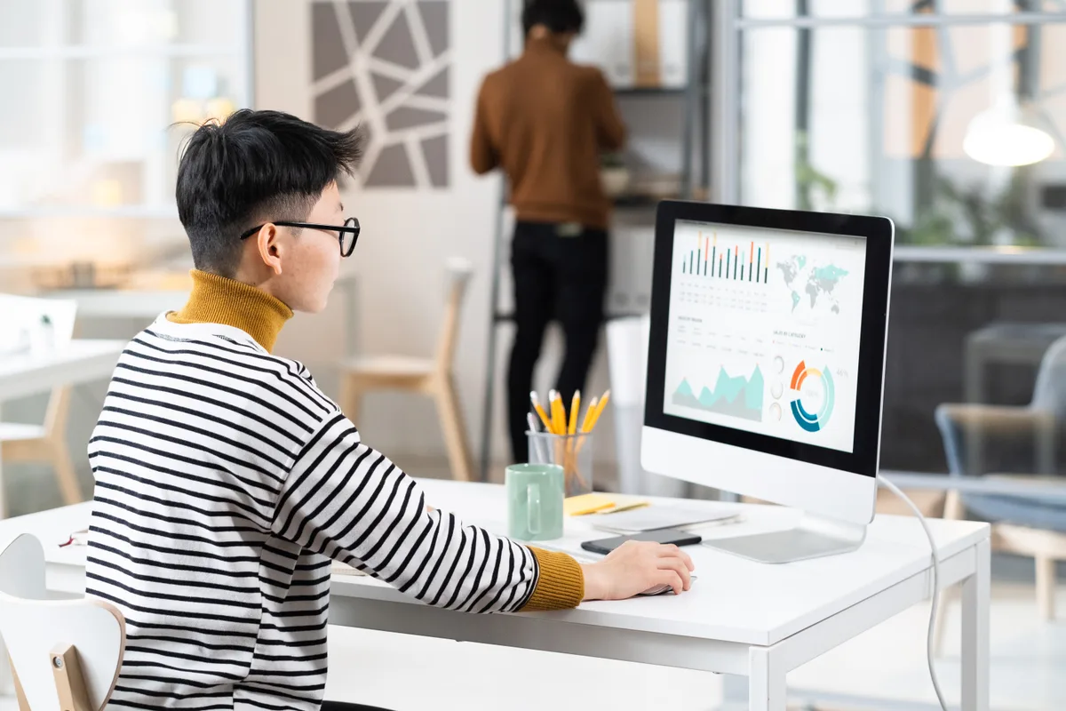 Business owner reviewing website analytics on a desktop monitor, comparing visitor numbers against contact form submissions