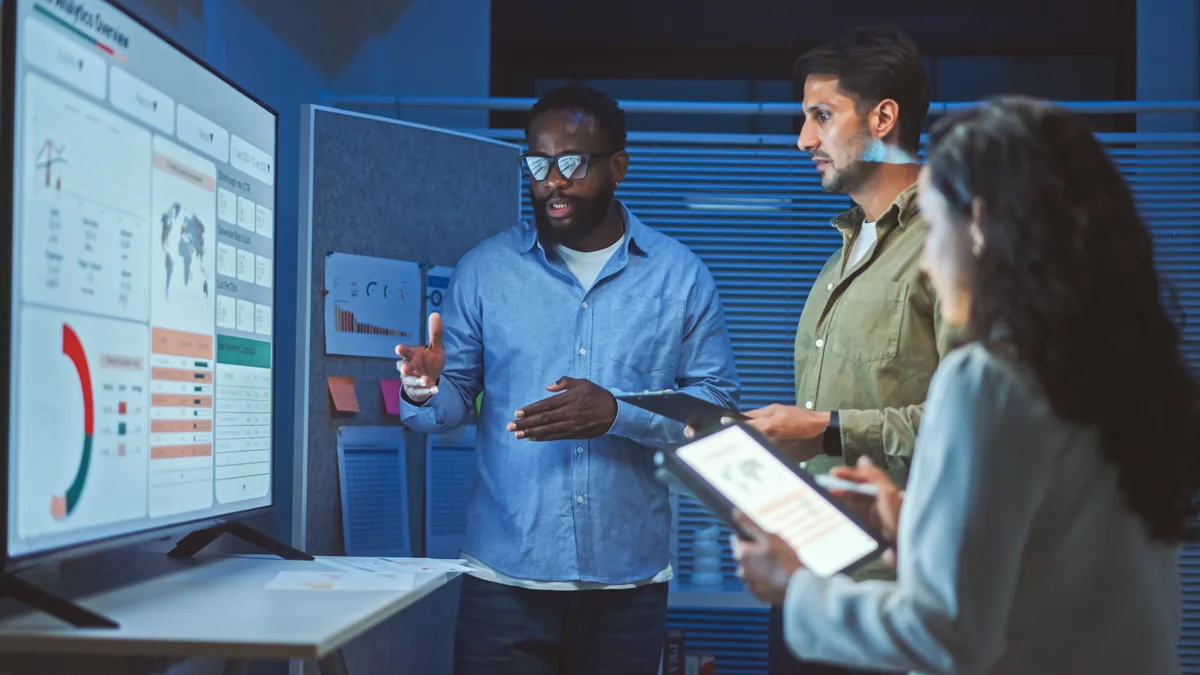 A digital marketer reviewing a Google Ads search terms report on a monitor to identify irrelevant queries draining the budget