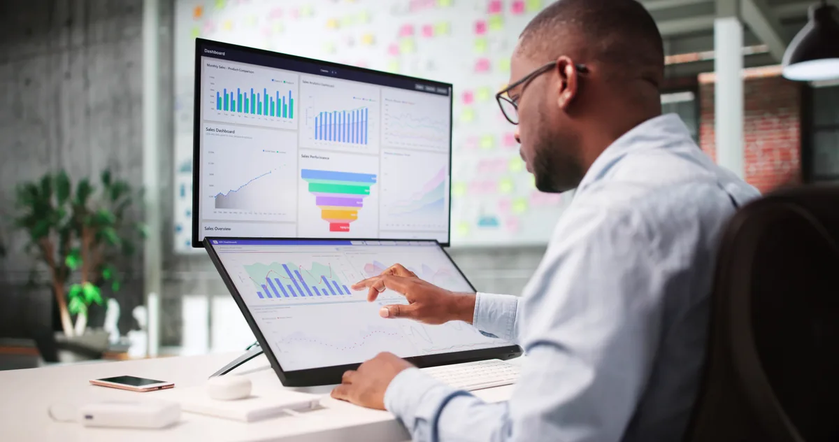 Marketing analyst reviewing an SEO traffic chart and a flat conversions chart side by side on a desktop monitor