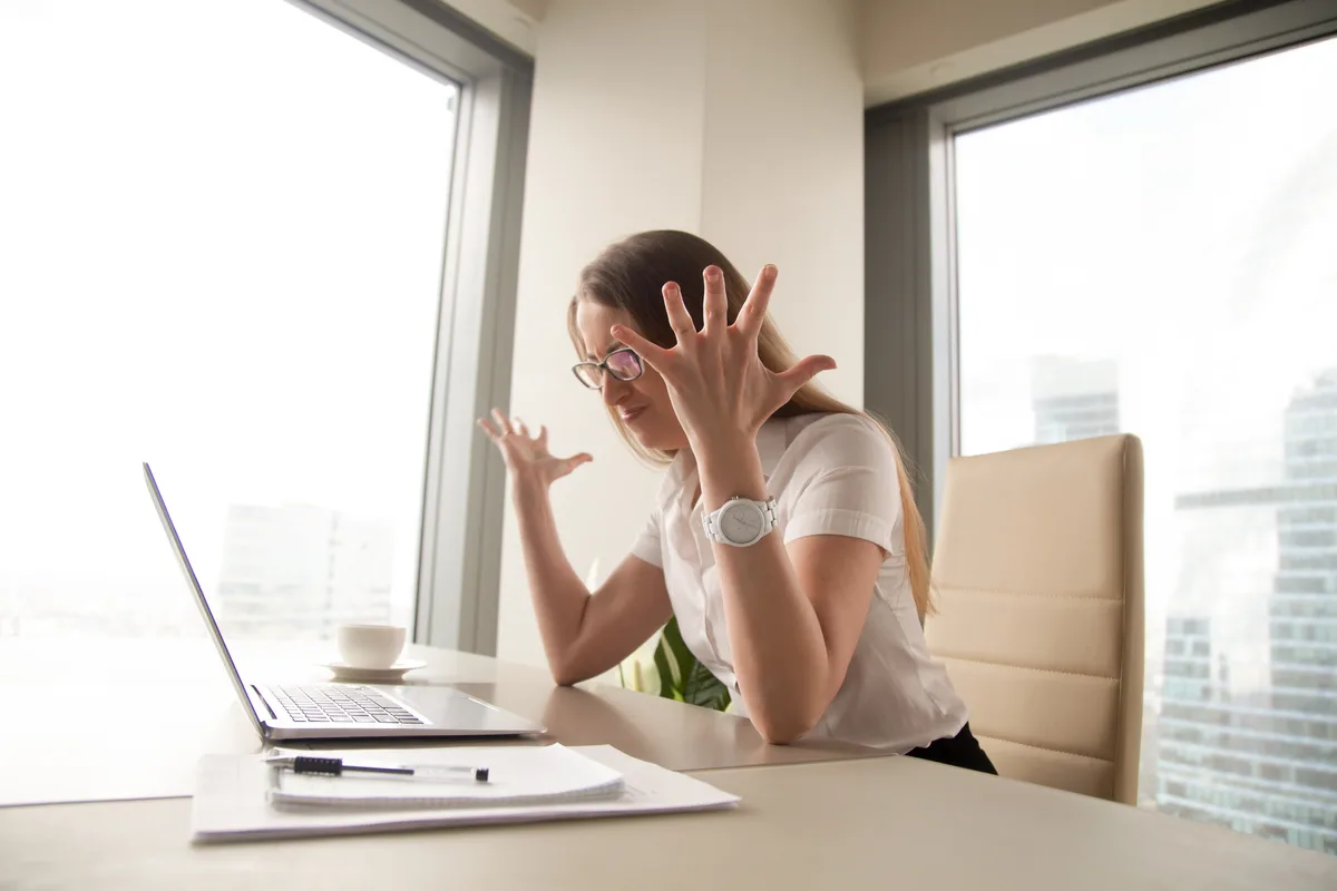 A service business owner at a desk reviewing lead reports on a laptop while holding a phone, looking concerned