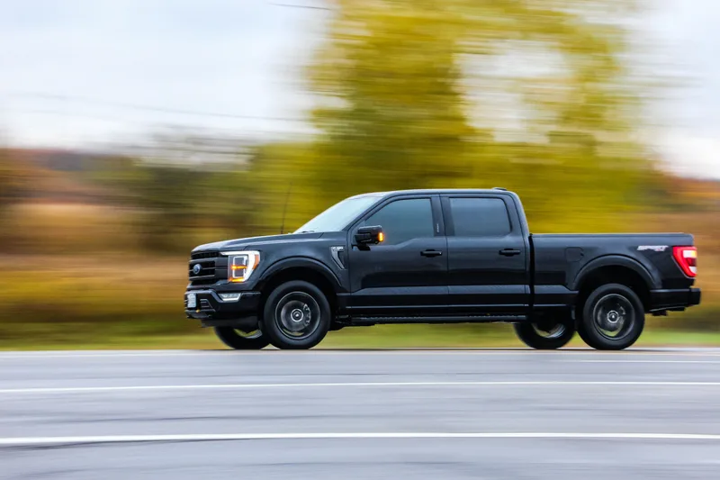Black Ford F-150 Sport SuperCrew driving past autumn trees