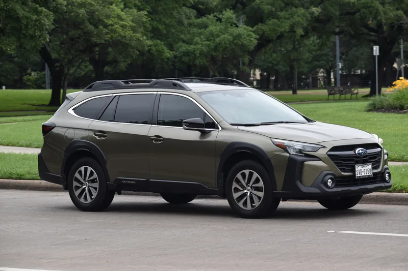 Autumn green Subaru Outback Onyx parked beside a leafy city park