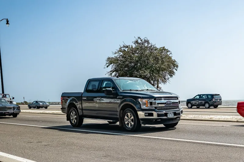 Grey Ford F-150 XLT SuperCrew driving along a seaside highway