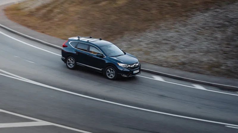 Dark blue Honda CR-V Touring driving along a curving coastal road