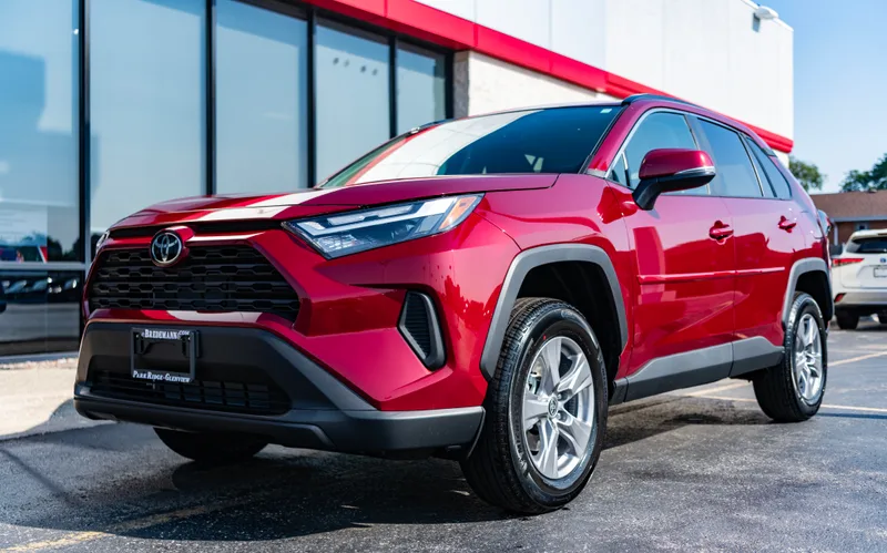 Ruby red Toyota RAV4 XLE parked in front of the dealership showroom