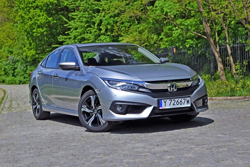 Silver Honda Civic Touring sedan parked on a tree-lined cobblestone lane
