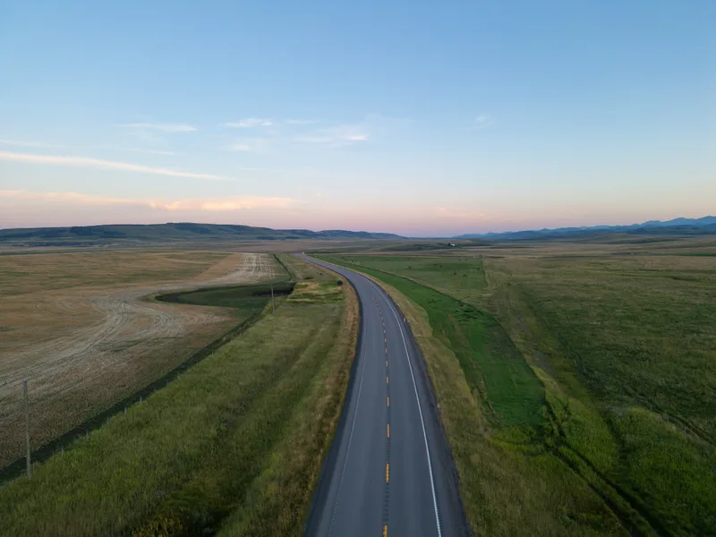 A highway running straight across open prairie at dusk