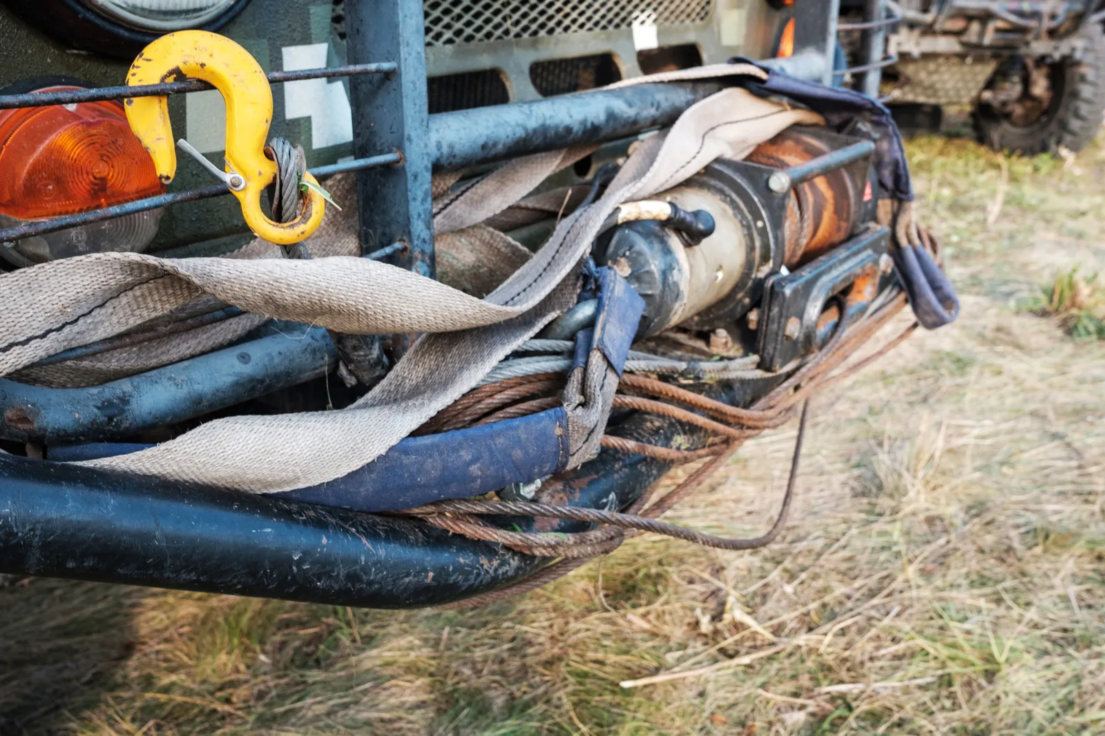 Recovery winch, cable, and straps rigged to the front of an SUV being pulled out of soft ground